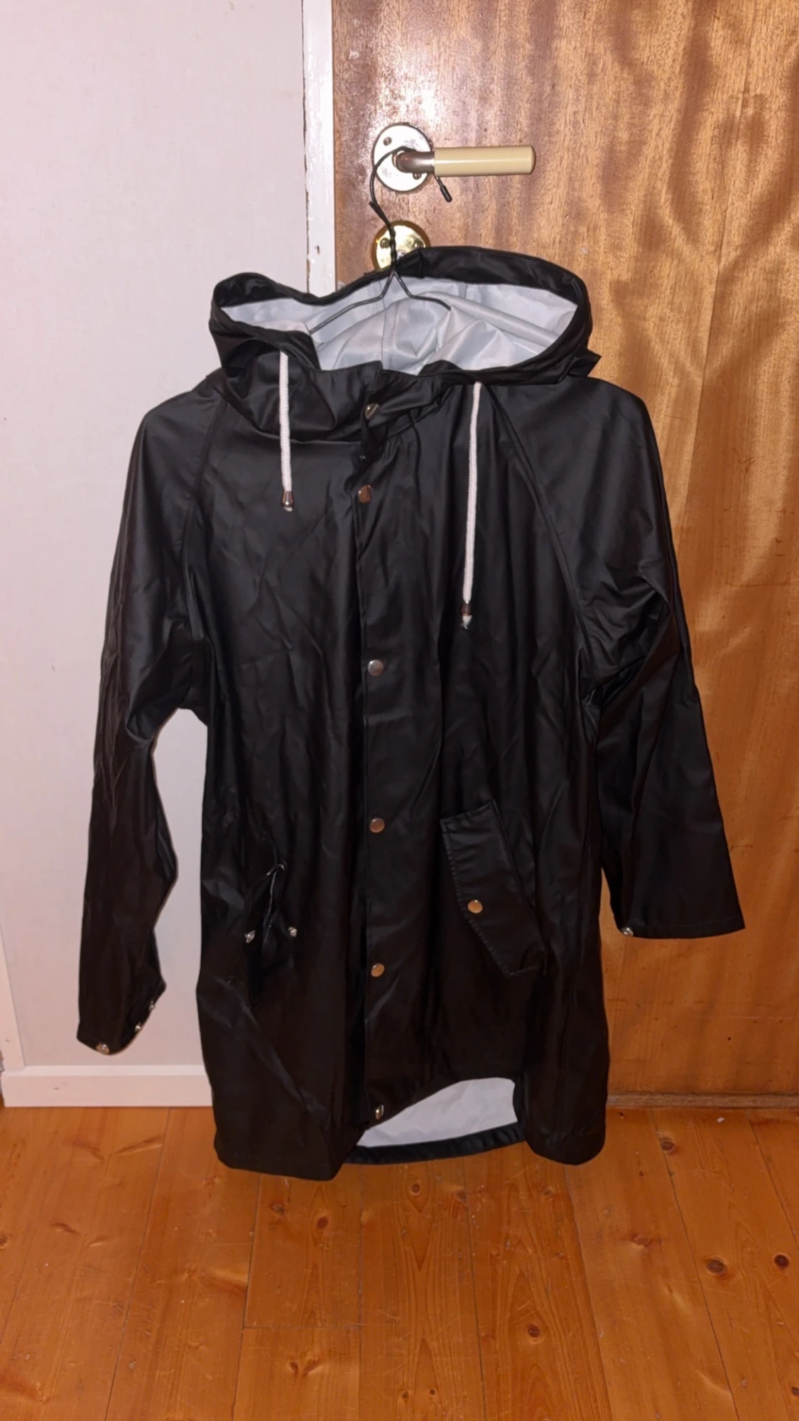 Svart regnjacka med huva och snörning