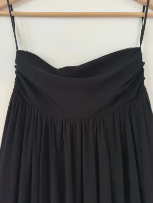 Svart axelbandslös klänning - Superfin svart axelbandslös klänning från H&M Divided med stor vidd i kjolen. Skönt elastiskt tyg och extra resår på toppen som gör att allt håller sig på plats. 😅 Perfekt både som sommarklänning som den är och som snygg festklänning till vinterns kalas med strumpbyxor under.   Hämtas i Stockholm eller skickas mot porto.