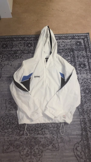 Zara windbreaker - Snabb leverans! 🚚 Dm för fler bilder! I fantastisk skick bara använd en gång! Säljer en fräsch vit vindjacka från Zara med blå och svarta detaljer på ärmarna och ryggen. Jackan har huva, half zip och snörning i midjan för en schysst passform. Perfekt för dig som gillar sportig stil och vill sticka ut med coola färgblock.