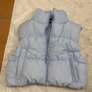 Svart och ljusblå väst storlek xxs H&M pris kan diskuteras  - Två puffiga västar, en i svart och en i ljusblått. Båda har hög krage, dragkedja framtill och praktiska fickor på sidorna. Pris kan diskuteras skriv vilken ni vil ha. 