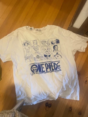 Vit One Piece t-shirt  - Säljer en vit t-shirt från newyorker i storlek XXL med stort One Piece-tryck på framsidan. T-shirten har korta ärmar och motiv med flera karaktärer från anime-serien. Materialet är mjuk bomull och passformen är normal. Perfekt för dig som älskar manga och anime!