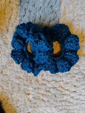 Set med två handgjorda scrunchies - Säljer ett set med två virkade scrunchies I ett turkiskt glittrigt garn. Jag har själv gjort dem och de är virkade runt en vanlig hårsnodd.