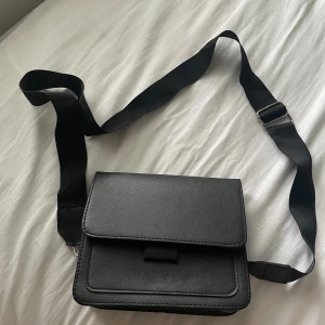 Svart axelremsväska  - Svart axelremsväska är med tjockt band. Knappt använd