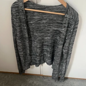 Gråmelerad kofta med lång ärm - Gråmelerad kofta med lång ärm och öppen front. Tunt och mjukt material som passar perfekt för lager-på-lager. Snyggt melerat mönster i olika grå toner ger en chill och avslappnad vibe.