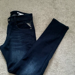 Replay ambass slim jeans - Säljer ett par mörkblå Replay Anbass jeans med klassisk femficksdesign och snygga detaljer. Jeansen har en slim passform och är tillverkade i stretchig bomullsdenim för extra komfort. Märkespatch bak i midjan och diskret Replay-logga vid fickan. Liten defekt vid vänster baksida. Pris kan diskuteras vid snabb affär, även öppen för byten. Tveka inte på att höra av er vid frågor eller funderingar!😇