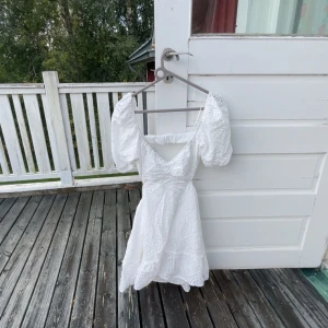 Vit klänning med puffärmar - Superfin vit kort klänning med broderade detaljer och puffärmar. Klänningen har v-ringning, öppen rygg och öppna sidor. Perfekt för sommarens alla tillfällen!🤍