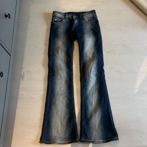 Blå bootcut jeans Cheap Monday 25/30 - Snygga blå bootcut jeans från weekday i storlek 25/30. Jeansen har en klassisk femficksmodell, slitna detaljer och ljusare tvätt längs benen. Materialet är 70% bomull, 28% polyester och 2% elastan för lite stretch. de är lite slitna nere men det var för att de var för små för mig så jag trampade lite på dem det är ett litet hål längst ner vid sömnen.