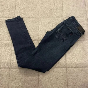 Mörkblå skinny jeans från Replay - Snygga mörkblå skinny jeans från Replay med klassisk femficksdesign och silverfärgade detaljer vid fickorna. Jeansen har normal midja och är tillverkade i stretchigt denim för en tight och bekväm passform. Perfekta för dig som gillar en stilren look.