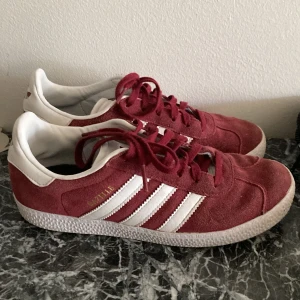 Adidas Gazelle vinröda sneakers mocka - Adidas Gazelle sneakers i vinrött mocka, perfekt skick, som nya. Original-innersulor saknas, tyvärr (glömde dem på semestern).  Kan mötas i centrala- eller norra Stockholm för inbetalning och överlämning. 