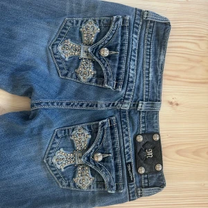 Miss Me blå bootcut jeans med detaljer - Snygga blå jeans från Miss Me i bootcut-modell. Säljer då dem var lite för stora! Midjemått 78cm! Jag har storlek 23 i true religion så dem bör passa nån med 25/26 kanske? Priset kan självklart diskuteras!!! 
