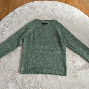 Grön stickad tröja från Vero Moda - Mysig grön stickad tröja från Vero Moda i storlek XS. Tröjan har rund hals, ribbade muddar och långärmad passform. Perfekt för dig som gillar enkel och chill stil med lite loose fit. Snygg att matcha med jeans eller kjol.