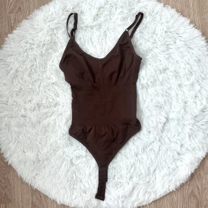 Brun ribbad bodysuit med smala axelband - Säljer en brun bodysuit med smala, justerbara axelband och ribbad struktur. Passar storlek XS-S (32-34), midjan upp till 65cm.