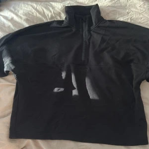 Svart half zip sweatshirt Aim'n XS - Svart sweatshirt från Aim'n i storlek XS med half zip och hög krage. Tröjan har broderad logga framtill och är långärmad med muddar vid ärmslut. Perfekt för chill eller träning, i mjukt bomullsmaterial.