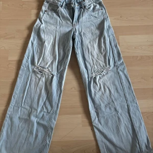 Ljusblå jeans med slitningar Kappahl 164 - Ljusblå jeans från Kappahl i storlek 164. Modellen har raka ben och coola slitningar över knäna. Klassisk femficksdesign och resår i midjan för extra komfort. Perfekta för en avslappnad och trendig look.