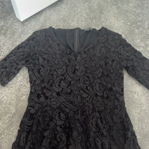 Svart blus från STOCKH LM - Supersnygg svart blus från STOCKH LM i storlek 38. Blusen har v-ringning, trekvartsärm och är täckt av vacker spets med blommigt mönster. Dragkedja i ryggen för enkel påklädning. Perfekt för dig som vill sticka ut med en elegant look.