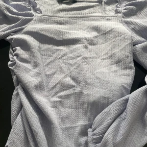 Ljuslila blus från Vero Moda - Supersöt ljuslila blus från Vero Moda med puffiga ärmar och en strukturerad, ribbad känsla i tyget. Blusen har en rak passform och är perfekt för dig som gillar en enkel men trendig look. Materialet känns mjukt och bekvämt mot huden.