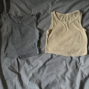 2 ribbade linnetoppar från Esmara - Säljer två ribbade linnetoppar från Esmara i storlek S. En är grå och den andra är beige, båda är ärmlösa med rund halsringning och croppad passform. Perfekta att matcha med jeans eller kjol för en enkel och snygg look.