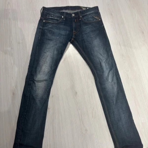 Replay Jeto jeans blå, storlek 32/32 - Snygga Replay Jeto jeans i mörkblå tvätt med slitningar och kontrastsömmar. Klassisk femficksmodell med raka ben och normal passform. Märkespatch bak i midjan och coola detaljer på bakfickorna. Perfekta för dig som gillar stilrena jeans med edge.