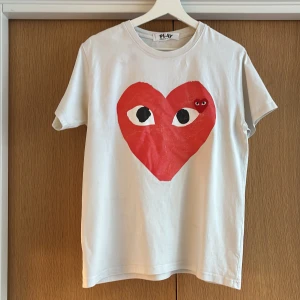 Vit Comme des Garçons Play t-shirt - Säljer en vit t-shirt från Comme des Garçons. Riktigt fet och perfekt för dig som vill sticka ut men samtidigt klä dig avslappnat. Skriv vid minsta frågan! Är large men passar även medium