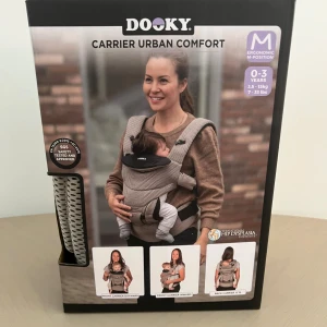 Dooky bärsele Urban Comfort beige mesh - Säljer en Dooky Urban Comfort bärsele i beige mesh med svarta detaljer. Ergonomisk design med justerbara axelremmar, midjebälte och stöd för huvud och ben. Selen är luftig och har flera bärpositioner. Perfekt för dig som vill bära ditt barn bekvämt och stilrent.