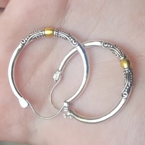  Helt nya Silvriga örhängen med gul detalj -  Helt nya Runda silvriga örhängen med snygga detaljer och en gul metallpärla på varje. De har ett klassiskt klicklås och dekorerade mönster längs kanterna som ger en cool vintagekänsla. Perfekt för dig som gillar att sticka ut med accessoarer. 3 cm 