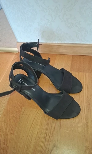 Svarta klackar från DinSko  - Säljer ett par svarta klackar från DinSko med bred klack och öppen tå. Skorna har en snygg rem runt ankeln med spänne och är tillverkade i mocka för en mjuk och lyxig känsla. Perfekta för dig som gillar stilrena och trendiga skor med lite höjd.