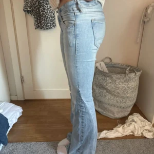Ljusblå bootcut jeans - Snygga ljusblå jeans med bootcut passform och klassisk femficksdesign. Jeansen har låg midja och är tillverkade i mjukt denim-material som sitter skönt. Perfekt för dig som gillar en avslappnad men trendig look.