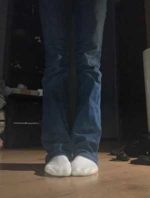 True Religion blå bootcut jeans - Säljer ett par snygga blå jeans från True Religion med klassiska vita sömmar och ikoniska bakfickor. Modellen har bootcut-ben och normal passform, med låg midja och slitstarka detaljer. Perfekt för dig som gillar streetstyle och vill sticka ut.