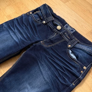 Mörkblå jeans från Monday - Snygga mörkblå jeans från märket Monday med klassisk femficksdesign och kontrastsömmar. Jeansen är bootcut och är tillverkade i slitstarkt denim med lätt tvättade detaljer framtill. Perfekt för dig som gillar en enkel och stilren look. De är ca 32-33 cm rakt över midjan!
