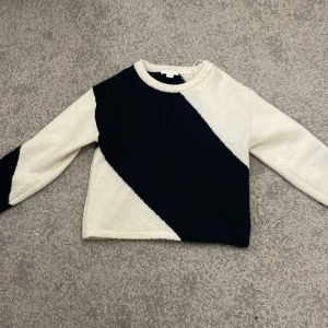 Svartvit stickad tröja Gina Tricot - Snygg stickad tröja från Gina Tricot i storlek 146/152. Tröjan har ett coolt diagonalt mönster i svart och vitt, med långärmade och ribbad halsringning. Perfekt för dig som gillar stilrena kontraster och mjuka material.