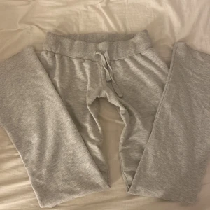 Grå mjukisbyxor från Nelly, strl S - Supermysiga grå Lågmidjade mjukisbyxor från Nelly i storlek S. De har en bred ribbad midja med snörning och är gjorda i mjukt bomullsmaterial. Perfekta för chill dagar hemma eller när du vill vara extra bekväm. Klassisk rak passform och stilren look.