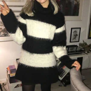 Randig stickad poloklänning från & Other Stories - Heej! Säljer min Mysiga oversized poloklänning från & Other Stories med breda svarta och vita ränder. Tröjan är stickad i fluffigt material, har lång ärm och hög polokrage. Perfekt för kalla dagar och ger en cool statement-look. Endast använd vid ett tillfälle, så gott som ny och köptes för ca 1200 kr.