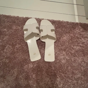 Vita sandaler  - Snygga vita sandaler från H&M i storlek 37. De har en fyrkantig tå och breda remmar med synliga sömmar. Tillverkade i syntetmaterial. Bra skick. Skriv för mer💕💕