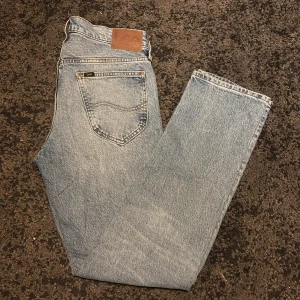 Lee Daren Zip Fly ljusblå jeans W30 L32 - Säljer ett par klassiska Lee Daren Zip Fly jeans i ljusblå tvätt. Modellen har rak passform, normal midja och dragkedja. Jeansen har fem fickor och Lee-logga på bakfickan samt läderpatch i midjan. Perfekt för dig som gillar tidlös denimstil.