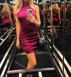 Klänning i satin - Säljer en elegant satinklänning med hög hals och ärmlös design. 