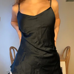 Marinblå  intimissimi sidentop  - Svart kort slipklänning i satin med smala axelband och v-ringad halsringning. Klänningen har en slät, glansig yta och en enkel, elegant siluett som sitter snyggt mot kroppen. Anvönd 3 ggr och 100% siden därav priset! Nypris: 600kr❤️