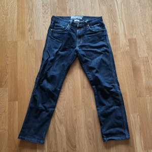 Mörkblå jeans från J.Lindeberg - Snygga mörkblå jeans från J.Lindeberg med klassisk femficksdesign och kontrastsömmar. Modellen har raka ben och normal passform, med diskret logopatch bak i midjan. Perfekt för dig som gillar stilrena och tidlösa jeans.