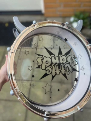 Little Bands Trumma - Rolig och färgglad barntrumma från Little Bands, perfekt för unga musikälskare. Trumman har stjärnmönster och är i gott skick med endast mindre tecken på användning. Lätt att hålla och spela på, idealisk för lek och musikträning.