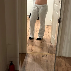 Grå mjukisbyxor med snörning - Säljer ett par ljusgrå mjukisbyxor med snörning i midjan. Byxorna har en loose passform och raka ben, perfekta för chill dagar. Tillverkade i mjukt bomullsmaterial som känns skönt mot huden. Enkla att matcha med hoodies eller t-shirts.