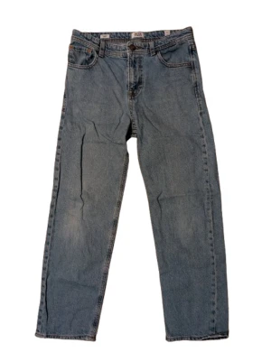 Ljus blå jeans från Jack & Jones - Klassiska blå jeans från Jack & Jones med relaxed fit och raka ben. Jeansen har fem fickor, bälteshällor och knappgylf. Tillverkade i slitstarkt denim med snygg tvättad look och kontrastsömmar. Perfekta för en avslappnad stil.