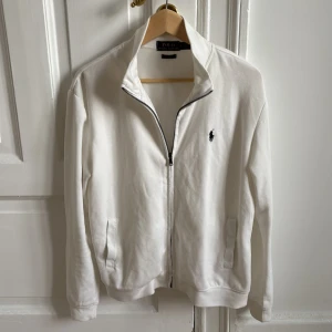 Ralph Lauren zip vit - Vit kofta från Polo Ralph Lauren i fantastiskt skick. Perfekt för kallare tider samt håller den otrolig klass och kvalité. Den är liten i storlek så sitter mer som M. Hör av er vid intresse!