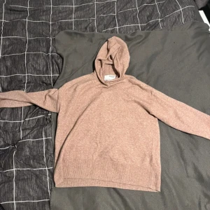 Beige hoodie från Selected Femme - Mysig beige hoodie från Selected Femme med ribbade muddar vid ärmslut och nederkant. Tröjan har huva och är långärmad, tillverkad i mjukt stickat material som känns skönt mot huden. Använd högst 2 gånger.
