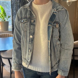 Ljusblå jeansjacka med knappar - Säljer en klassisk ljusblå jeansjacka med snygga silverfärgade knappar framtill och på bröstfickorna. Jackan har krage, raka långa ärmar och coola sömmar som ger en schysst look. Perfekt att slänga över en hoodie eller t-shirt för en chill stil.