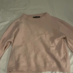 Ljusrosa stickad tröja från 157 - Mysig ljusrosa stickad tröja från 157 med rund hals och ribbade muddar vid ärmslut och nederkant. Perfekt för dig som gillar enkel och clean stil. Tröjan har lång ärm och är i en mjuk stickad kvalitet som känns skön mot huden.