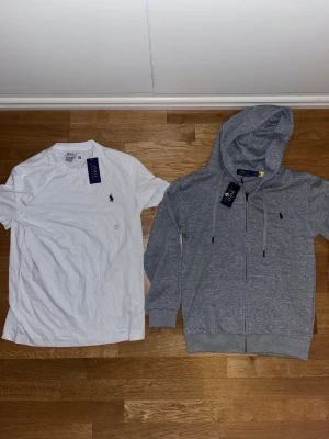 Vit t-shirt från Polo Ralph Lauren - Vit t-shirt från Polo Ralph Lauren med klassisk rund hals och korta ärmar. Slim fit-modell i mjuk bomull med den ikoniska blå broderade loggan på bröstet. Perfekt basic med stilren design och skön passform.