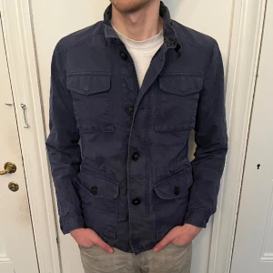 MASSIMO DUTTI - FIELDJACKA - Field jacket från massimo dutti i storlek Medium perfekt för vintern, skicket är ungefär 6-7/10 en av knapparna har gått av men den medföljer ändå ifall man vill fixa den. Nypris ligger på 2000 men eftersom defekten säljer jag för 450kr!