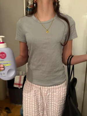 Ljusgrå ribbad t-shirt - Säljer en ljusgrå ribbad t-shirt med rund hals och korta ärmar. T-shirten har en enkel och clean look, perfekt för dig som gillar basic plagg med lite struktur. Materialet känns mjukt och skönt mot huden, och passformen är normal. Enkelt att matcha med jeans eller shorts.