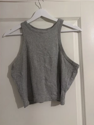 Grå ribbad linnetopp från HM/DIVIDED - Säljer en grå ribbad linnetopp från DIVIDED i storlek L. Toppen har ärmlös design med breda axelband med hög och rund halsringning. Perfekt för sommaren och enkel att matcha med jeans eller shorts. Materialet är mjukt och stretchigt för skön passform. 💗