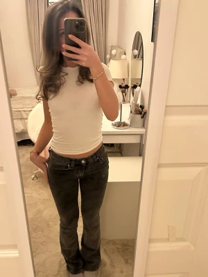 Låg midjade svarta bootcut jeans - Säljer ett par svarta jeans med låg midja och bootcut-modell. Jeansen har klassiska fickor och synliga sömmar, och är i ett stretchigt jeansmaterial. 