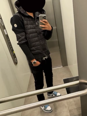 Svart pufferjacka från Moncler - Säljer en svart pufferjacka från Moncler med huva och dragkedja framtill. Jackan har quiltad front och släta ärmar med Moncler-logga på vänster arm. Perfekt för dig som gillar stilren och sportig look.